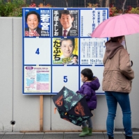 A boy and his mother browse local candidates on an election board outside a polling station as Japan\'s general election gets underway in Setagaya Ward on Sunday afternoon. | ROB GILHOOLY