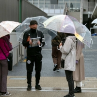 A man completes an exit survey after voting at a polling station as Japan\'s general election got underway in Setagaya Ward on Sunday. According to ward official Yoshinari Ando, morning voting numbers at the station had been good compared with previous years, adding they had tailed off significantly in the afternoon as the rain started to fall. Early voting numbers would seem to suggest a \"decent turnout,\" he says, adding that the number of young voters — frequently low among Japan\'s voting public — had also been reasonably favorable, likely influenced by the polling station\'s proximity to youth culture capital Shimokitazawa. | ROB GILHOOLY