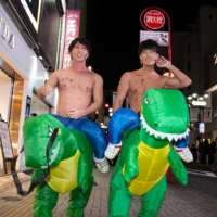 Two young men take their dinosaurs for a ride in Shibuya. | ROB GILHOOLY