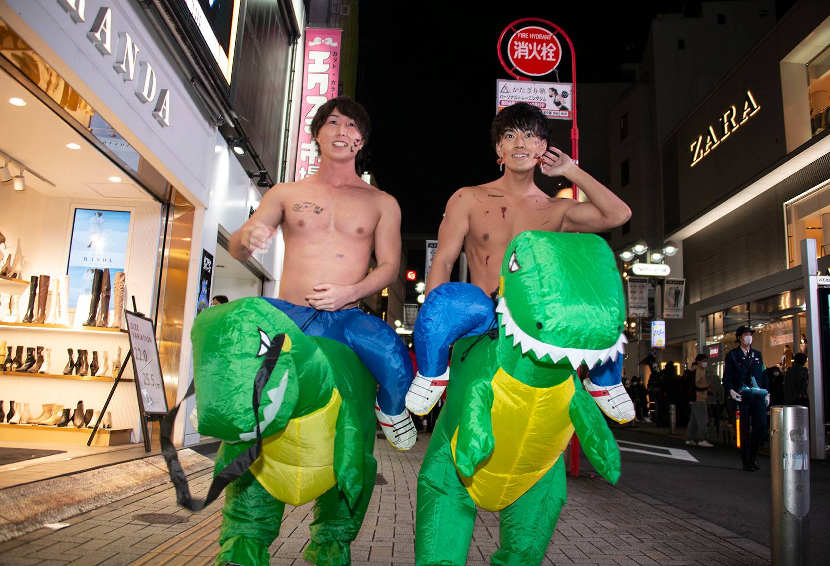 Two young men take their dinosaurs for a ride in Shibuya. | ROB GILHOOLY