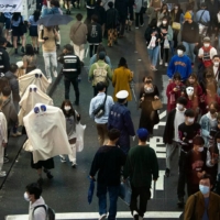 Halloween revelers fill the streets in central Shibuya on Sunday. Officials of Shibuya, which has become a popular gathering spot for Halloween events, and the police had requested people celebrate at home due to continuing concerns about the possible spread of the novel coronavirus. Shibuya even organized an online event for enjoying Halloween remotely. Nonetheless, thousands of revelers showed up over the weekend, with police struggling to keep the crowds moving across the famous scramble intersection in front of the station. | ROB GILHOOLY