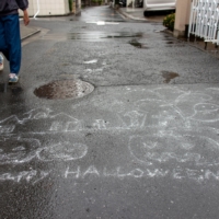 Pedestrians walk past a “Happy Halloween” message written with chalk on the asphalt in Setagaya Ward, Tokyo. This year, Halloween and a major election ended up sharing a date. Turnout among Japan\'s youth was expected to be lower than the 31% in the 2019 Upper House election — a far cry from countries such as Denmark, where it is around 80%. In the United States, around 50% of 18- to 29-year-olds voted in the 2020 presidential election — an 11-point increase over the 2016 ballot. | ROB GILHOOLY