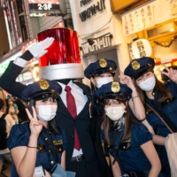 \"Sasuke,\" 33, has his photo taken with young women dressed up as police officers. Sasuke, whose cop car light outfit took him months to make, admits he never votes. \"Time is precious and I’d prefer to spend my free time making things like this,\" he says. \"I think it would make a difference if they could make elections more interesting for young people, maybe introduce something like an election animation, explaining why people should vote, what the merits of doing it are, or if they don’t vote this or that could happen. Also think it would make a big difference if voting online was introduced. I\'d vote if that was an option.\" | ROB GILHOOLY