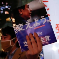 A man distributes the party leaflets before Yukio Edano, the leader of the Constitutional Democratic Party of Japan, speaks to voters on Saturday, a day before voting for the Lower House election, near Shinjuku Station in Tokyo. | REUTERS