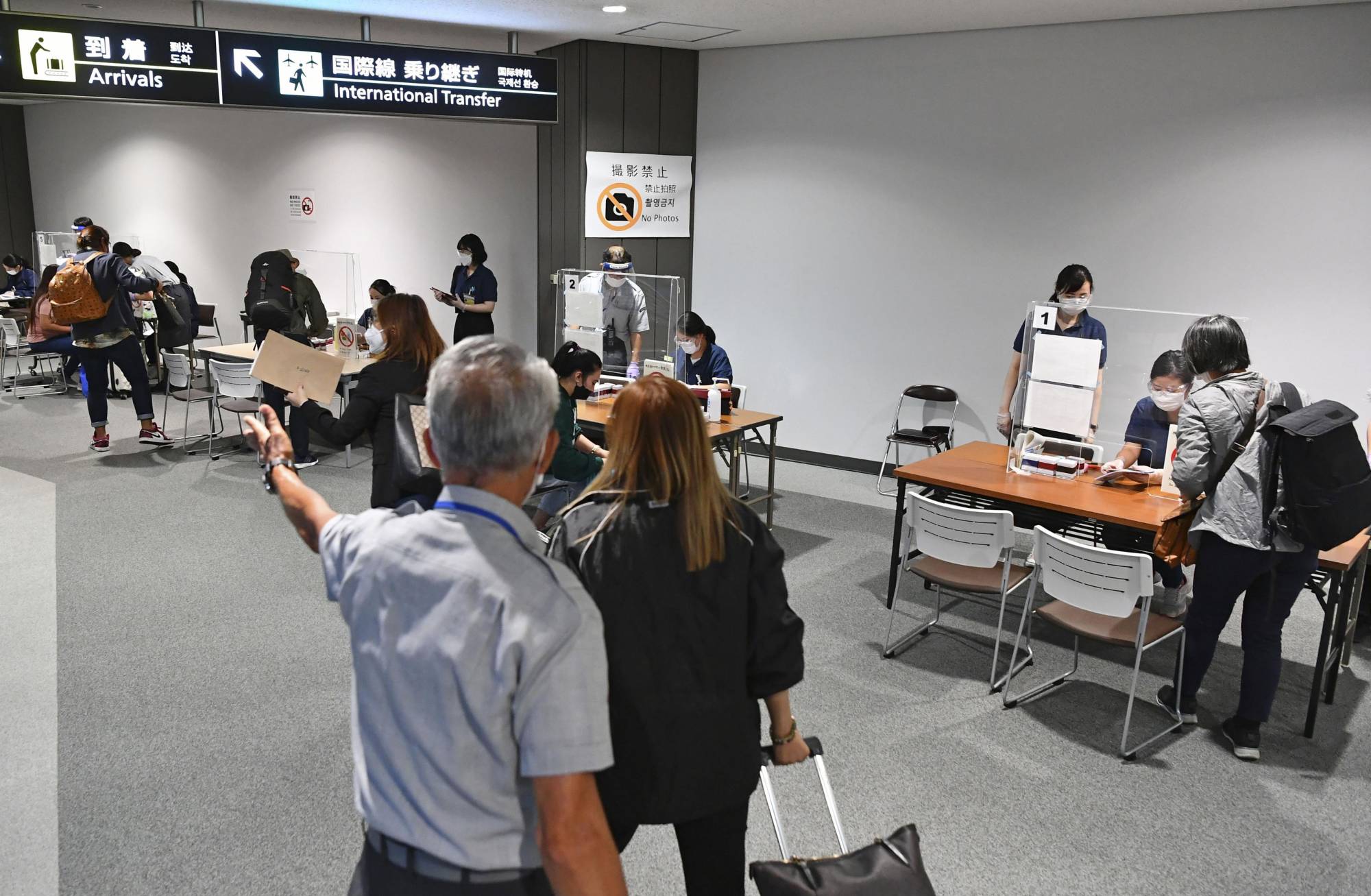 Officials at Narita Airport in Chiba Prefecture check travelers from abroad for negative results for COVID-19 in September. | KYODO