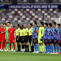 Players representing China and Japan line up for national anthems before their World Cup qualifier in Doha on Sept. 7. | REUTERS