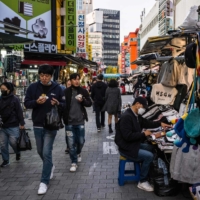 Pedestrians walk past stalls in Namdaemun Market in Seoul on Tuesday. | AFP-JIJI