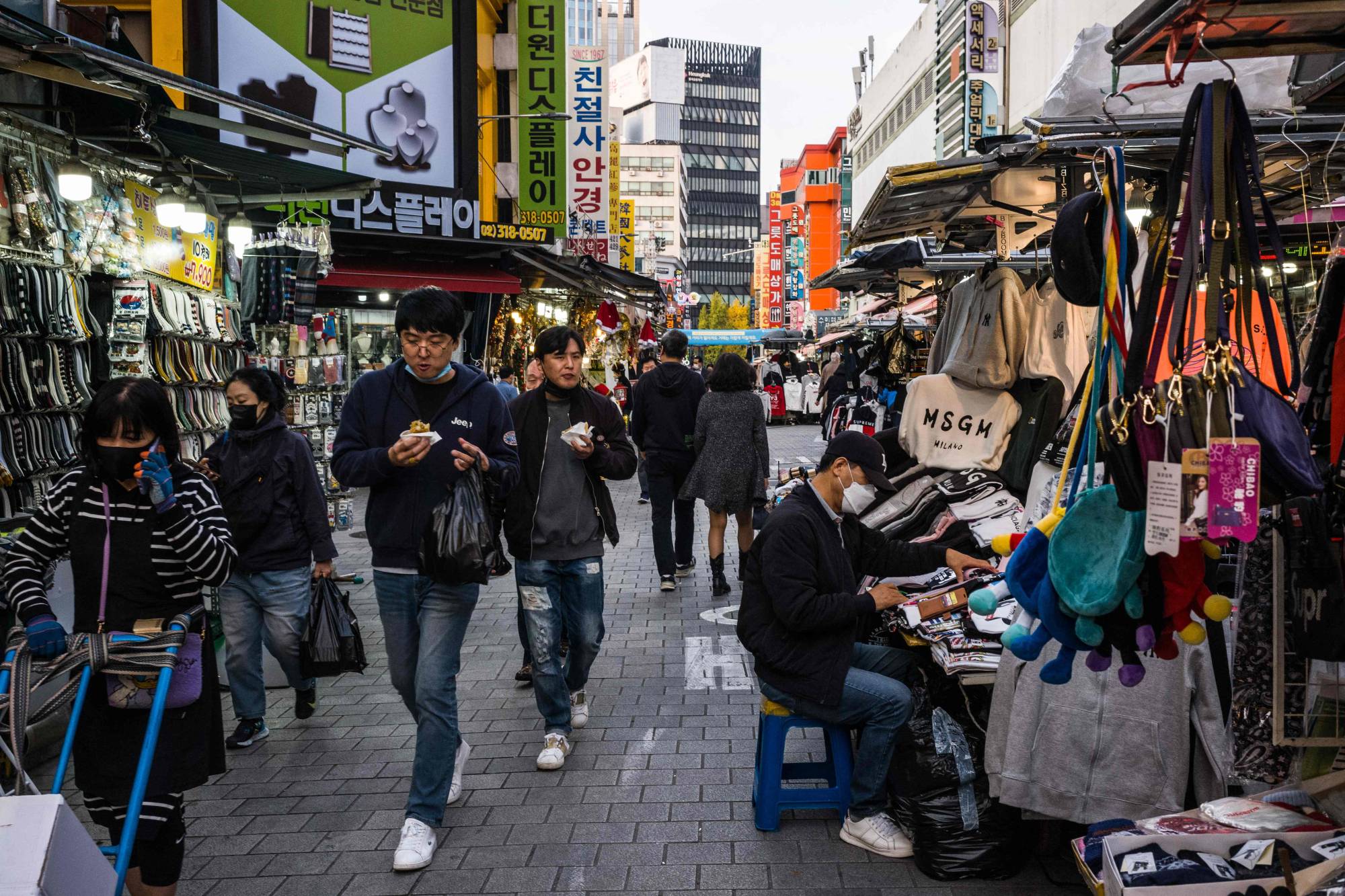 Pedestrians walk past stalls in Namdaemun Market in Seoul on Tuesday. | AFP-JIJI