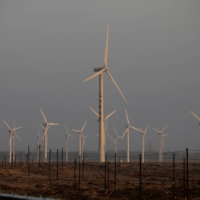A car drives near wind turbines for a power station in Gansu province, China, in September 2020. | REUTERS