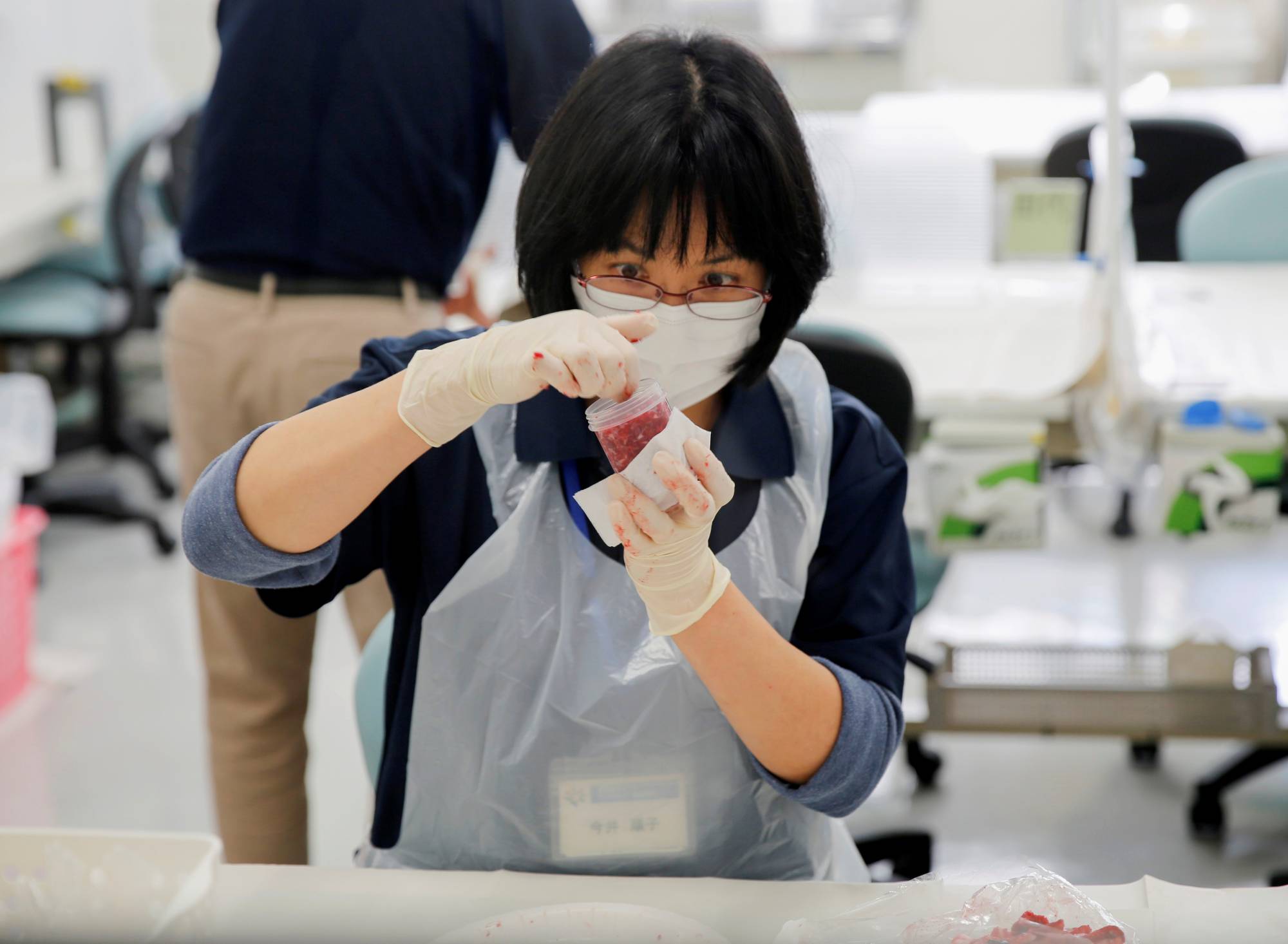 A laboratory technician puts chopped beef from cattle bred in Fukushima into a plastic container while preparing it for cesium testing at Fukushima Agricultural Technology Center. | Reuters