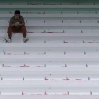 A man uses his phone at a playground in Hong Kong with seats marked with social distancing areas on Oct. 30. | BLOOMBERG