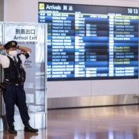 A police officer stands in the arrivals hall of Haneda Airport in Tokyo on Monday. | AFP-JIJI