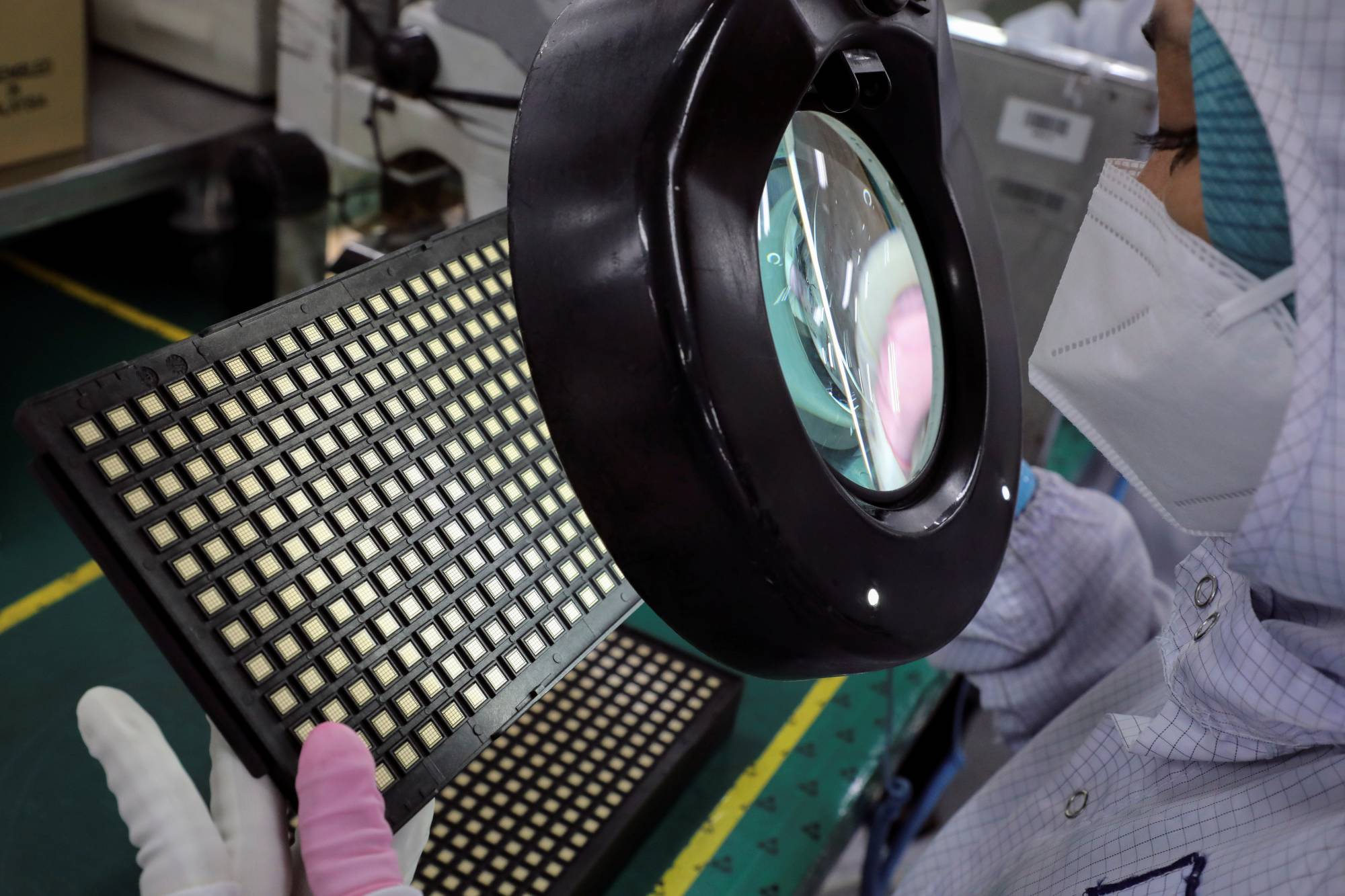 A worker inspects semiconductor chips at a chip packaging plant in Ipoh, Malaysia, on Oct. 15. | REUTERS