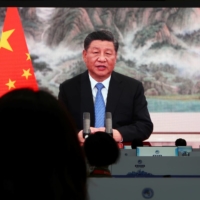 People watch as Chinese President Xi Jinping delivers a speech via video at the opening ceremony of the China International Import Expo in Shanghai on Thursday.  | REUTERS