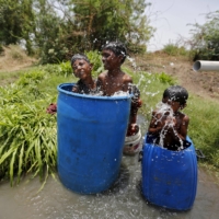 Children sit in containers filled with water as they cool themselves on a hot summer day on the outskirts of Ahmedabad, India. | REUTERS 