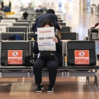 A quarantine agent waits for passengers arriving from overseas at the arrivals hall of Haneda Airport in Tokyo on Monday.
 | AFP-JIJI