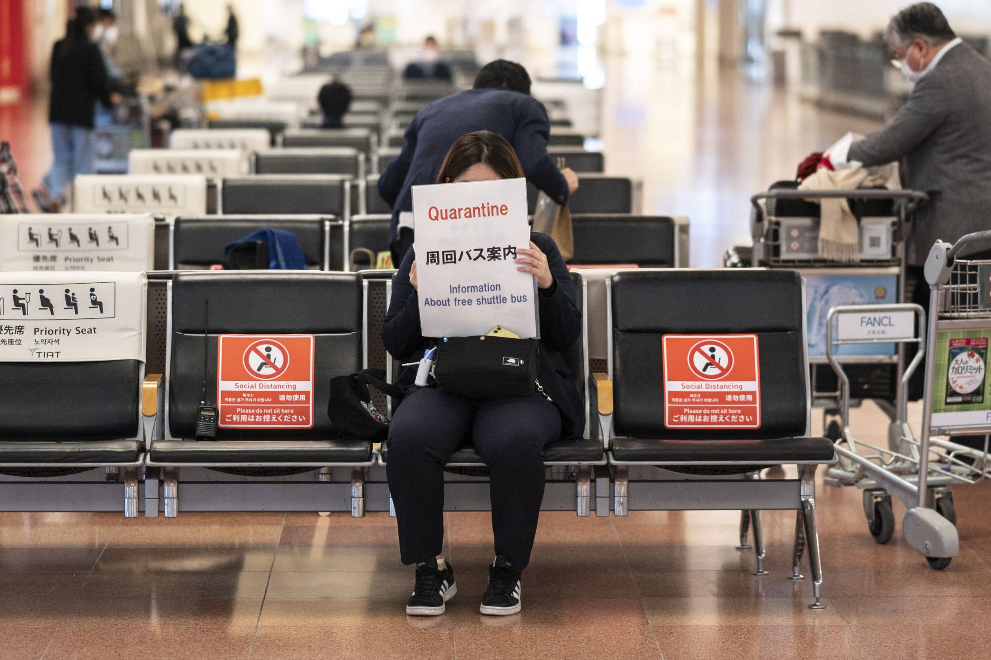 A quarantine agent waits for passengers arriving from overseas at the arrivals hall of Haneda Airport in Tokyo on Monday. | AFP-JIJI