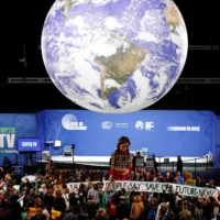 People gather around \"Little Amal,\" a 3.5 meter tall puppet of a young Syrian refugee girl, during the COP26 summit in Glasgow. | REUTERS