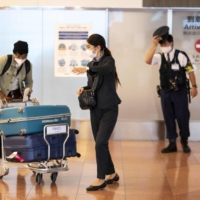 A passenger arriving from overseas is welcomed by a quarantine agent at the arrivals hall of Haneda Airport in Tokyo on Monday. | AFP-JIJI