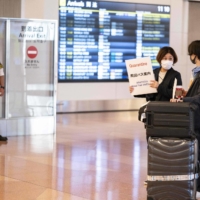 A passenger arriving from overseas is welcomed by a quarantine agent at the arrivals hall of Haneda Airport in Tokyo on Monday. | AFP-JIJI