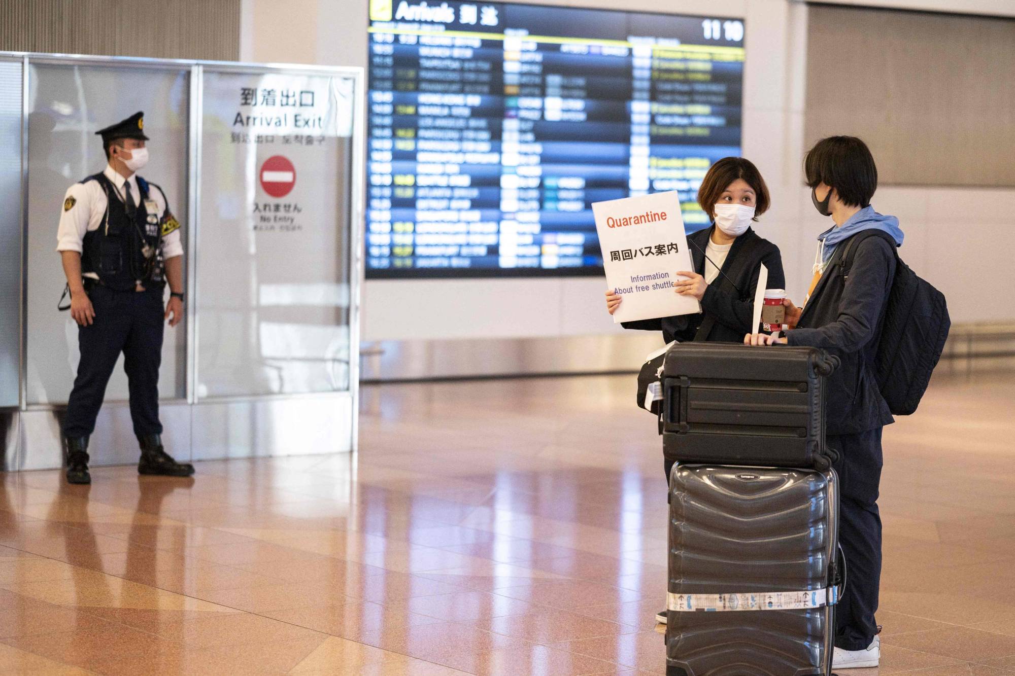 A passenger arriving from overseas is welcomed by a quarantine agent at the arrivals hall of Haneda Airport in Tokyo on Monday. | AFP-JIJI