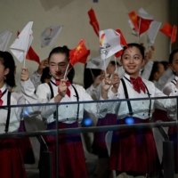 Children wave national flags during the Olympic flame welcoming ceremony ahead of the Beijing 2022 Winter Olympics, in the lobby of the Olympic Tower in Beijing on Oct. 20. | AFP-JIJI