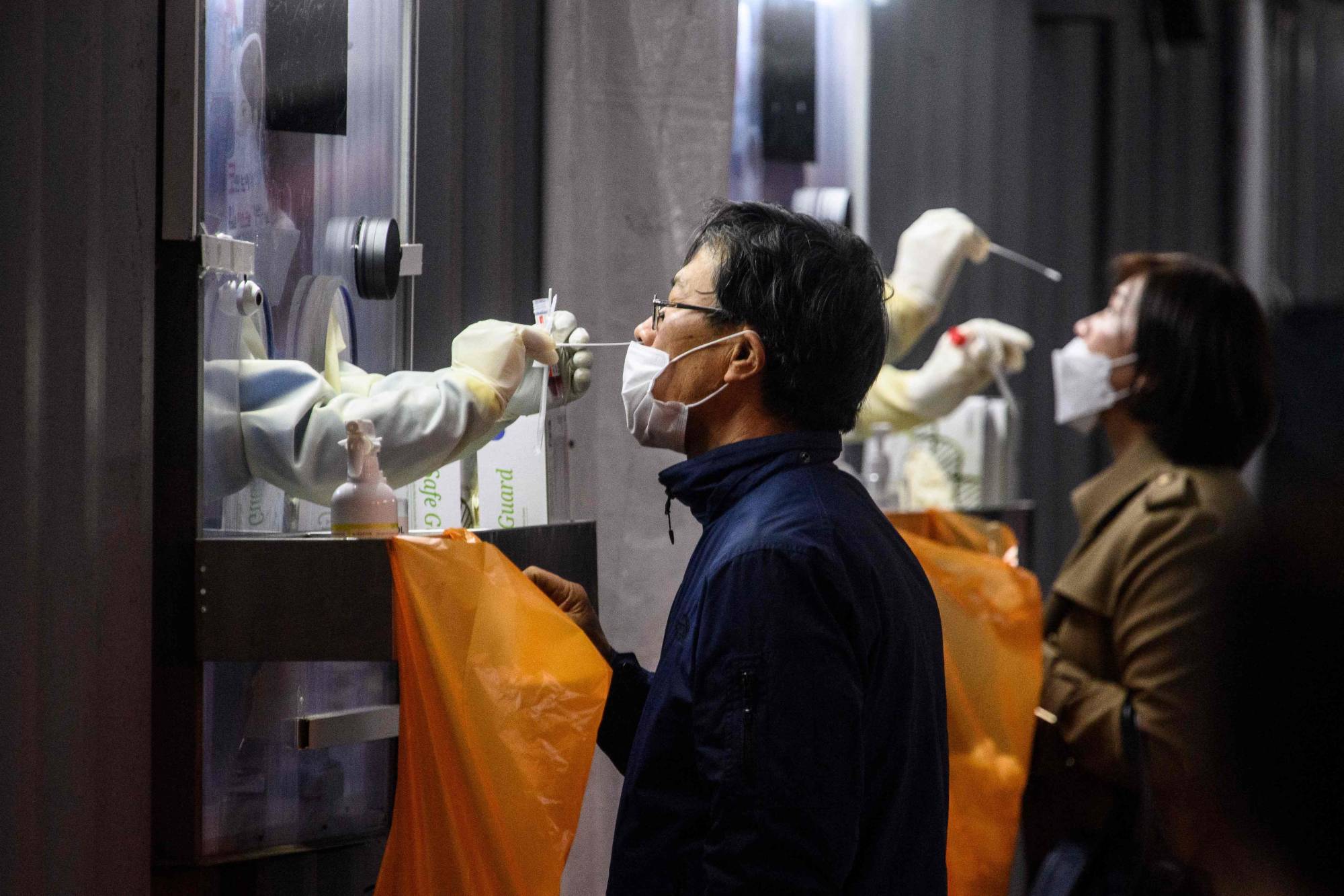 A man and woman undergo PCR tests at a COVID-19 testing center in Seoul on Nov. 3. | AFP-JIJI