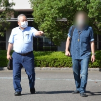 Kunihiro Kawada, who supports asylum-seekers in Japan, greets a Middle Eastern man who was granted provisional release from the Omura Immigration Center in Nagasaki Prefecture in October. The man’s face is blurred for privacy reasons. | NISHINIPPON SHIMBUN