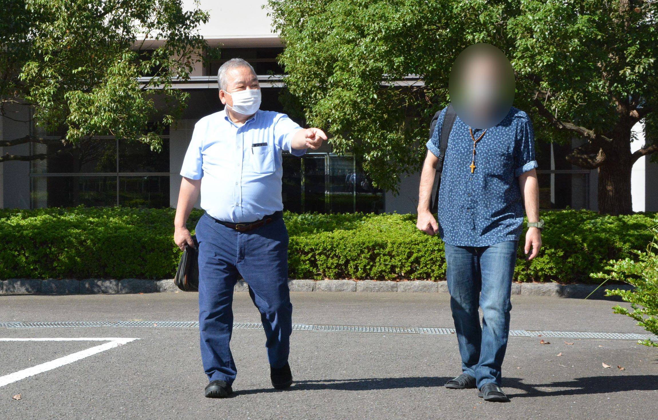 Kunihiro Kawada, who supports asylum-seekers in Japan, greets a Middle Eastern man who was granted provisional release from the Omura Immigration Center in Nagasaki Prefecture in October. The man’s face is blurred for privacy reasons. | NISHINIPPON SHIMBUN