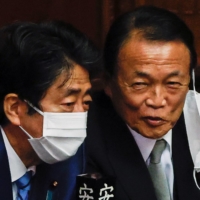 Former Prime Ministers Shinzo Abe (left) and Taro Aso speak during a parliamentary session at the Lower House in Tokyo on Nov. 10. | REUTERS
