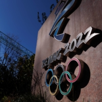 A woman walks past the Beijing 2022 logo that is seen outside the headquarters of the Beijing Organising Committee for the 2022 Winter Olympics and Paralympics in Beijing\'s Shougang Park on Nov. 10. | REUTERS