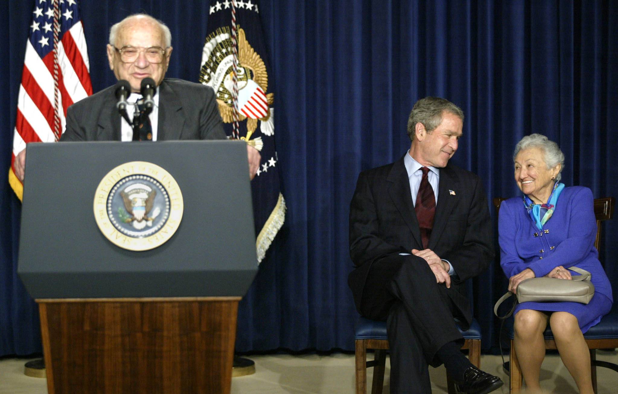 Milton Friedman addresses an event held in his honor in Washington in May 2002 as then-U.S. President George W. Bush chats with Friedman’s wife, Rose. | REUTERS 