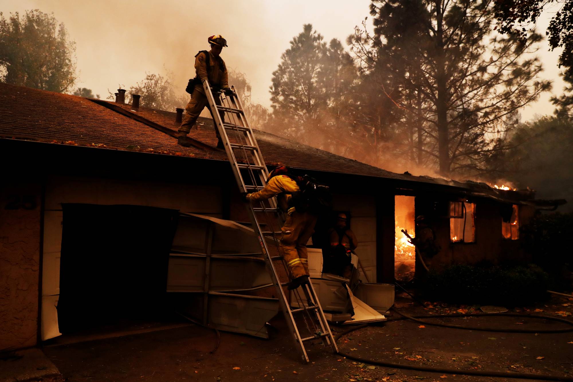 A Cal Fire firefighter climbs a ladder by a burning structure while battling the Camp Fire in Paradise, California, in November 2018.  | REUTERS