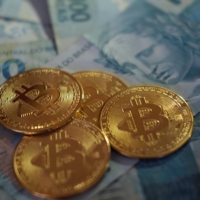 A representation of Bitcoin cryptocurrency are seen over Brazilian Real notes. Brazilian cryptocurrency firm 2TM Participacoes SA plans to branch out across Latin America by snapping up smaller firms in markets where their remittance services will thrive. | REUTERS
