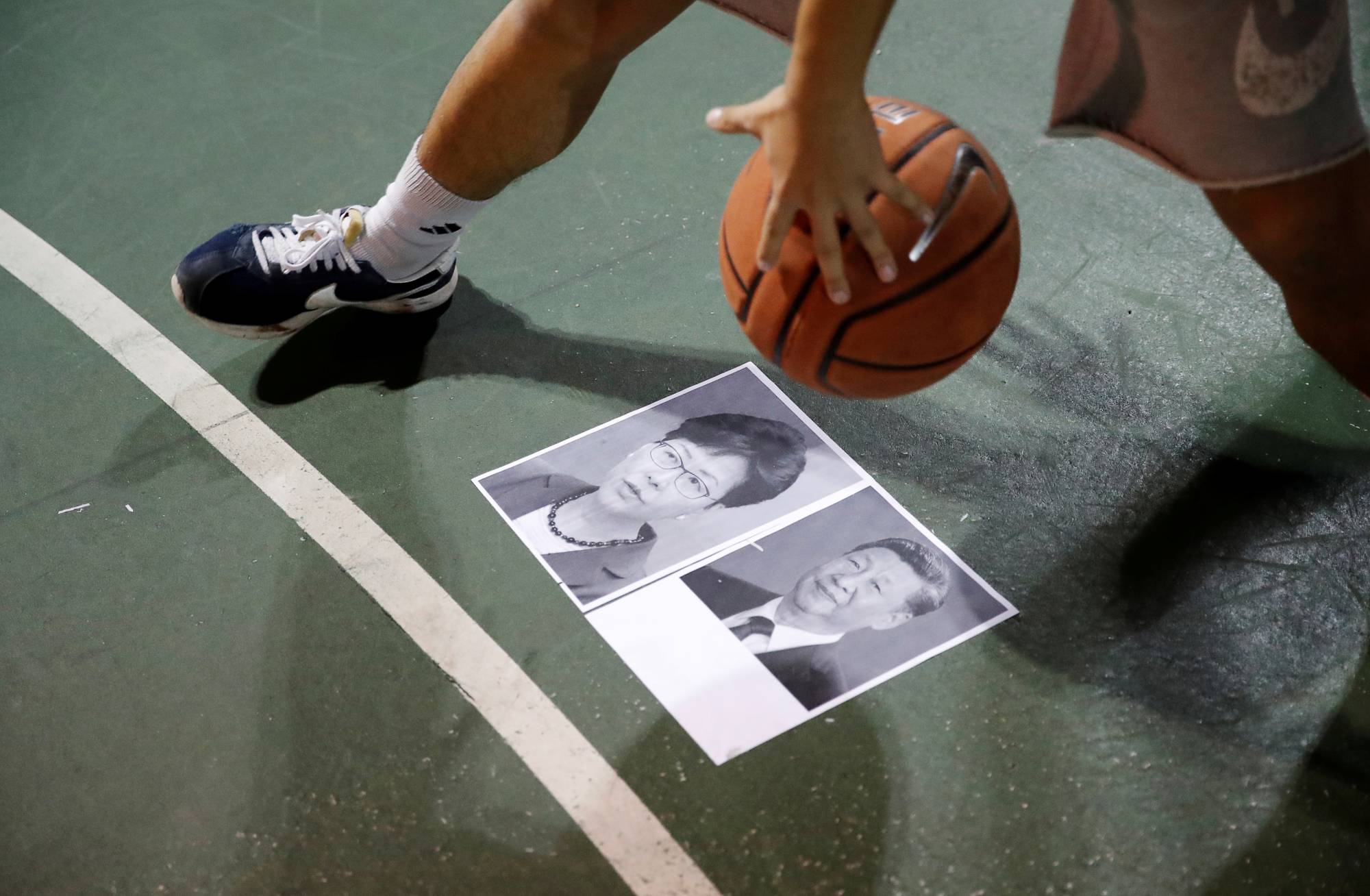 A protester dribbles a basketball over pictures of China's President Xi Jinping and Hong Kong Chief Executive Carrie Lam during a gathering in support of the Houston Rockets general manager Daryl Morey, who backed the pro-democracy movement in a tweet, in Hong Kong in October 2019. | Reuters