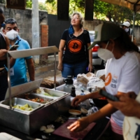 People buy traditional food from a local Bitcoin merchant at El Zonte Beach in Chiltiupan, El Salvador, on Nov. 18. | REUTERS 