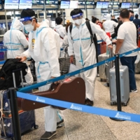 Passengers using protective equipment line up to check in for their flight at the Kuala Lumpur International Airport in Sepang, Malaysia, on Monday. | AFP-JIJI