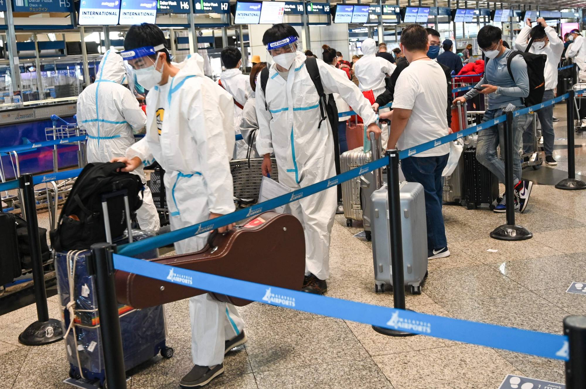 Passengers using protective equipment line up to check in for their flight at the Kuala Lumpur International Airport in Sepang, Malaysia, on Monday. | AFP-JIJI