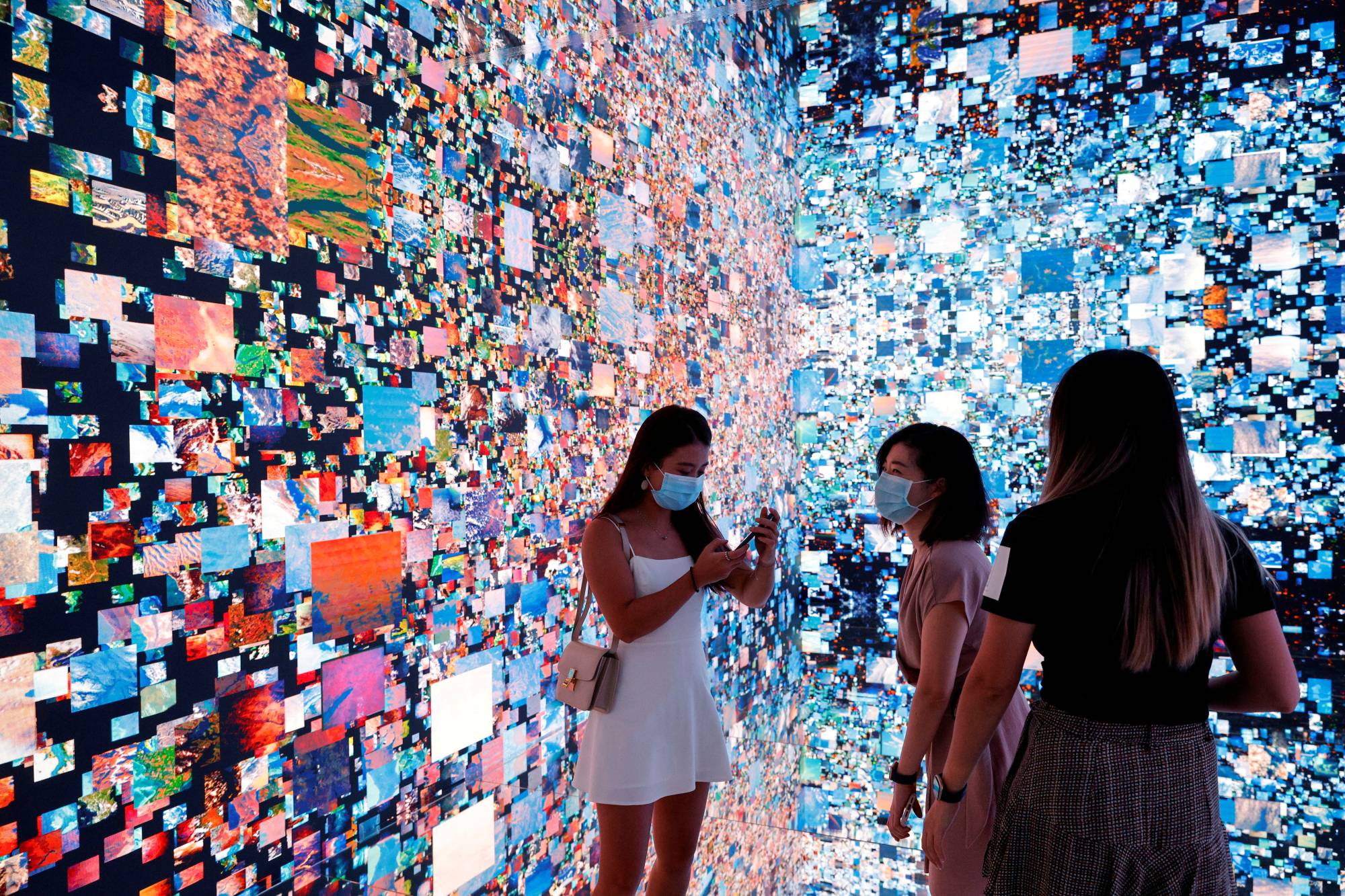 Visitors stand in front of an immersive art installation titled 'Machine Hallucinations - Space: Metaverse' by media artist Refik Anadol, which will be converted into NFT and auctioned online at Sotheby's, at the Digital Art Fair, in Hong Kong. | REUTERS