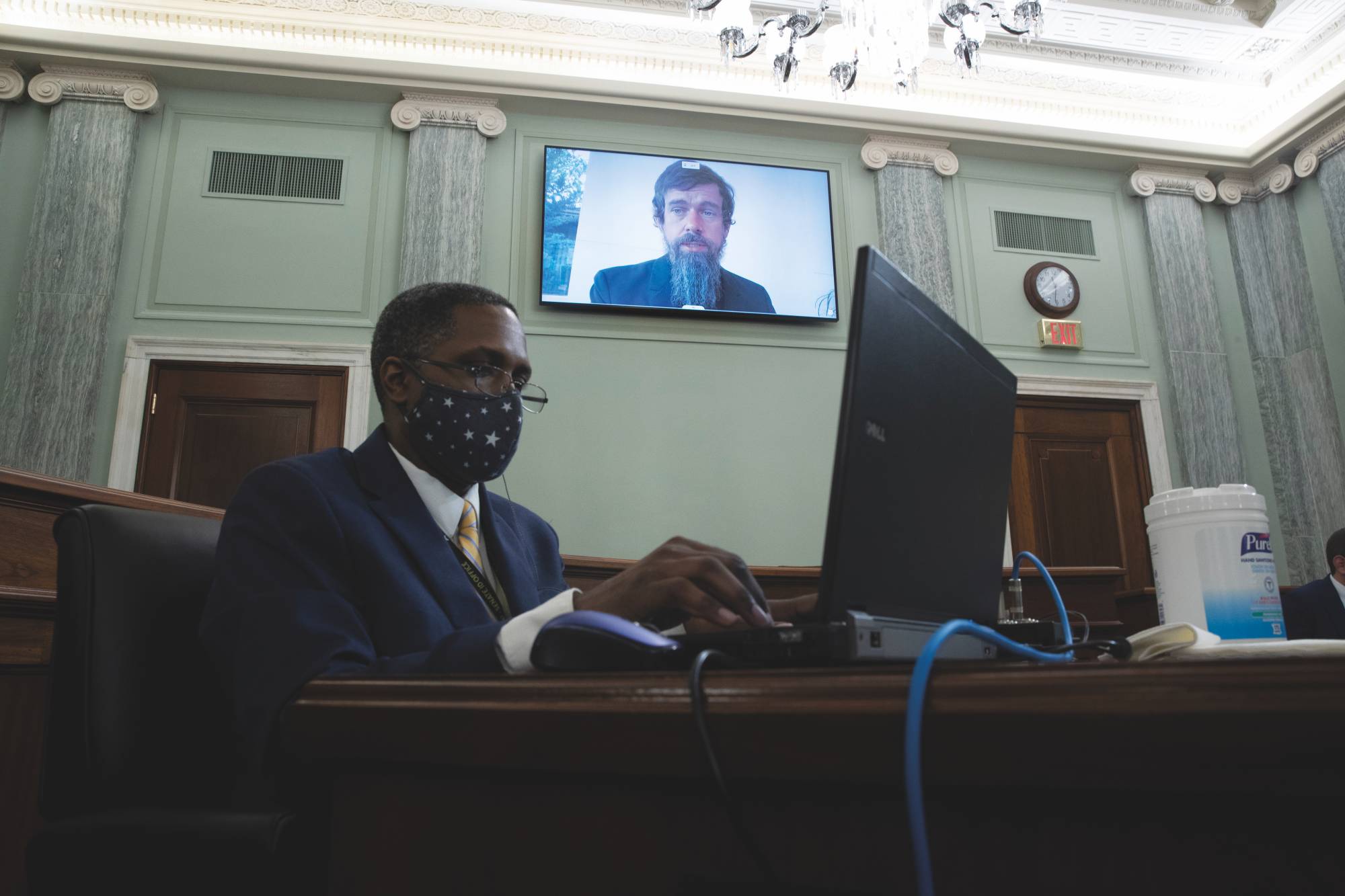 Twitter CEO Jack Dorsey appears on a monitor behind a stenographer as he testifies remotely during a Senate hearing on Big Tech in Washington on Oct. 28, 2020. | Michael Reynolds / Pool / Getty Images