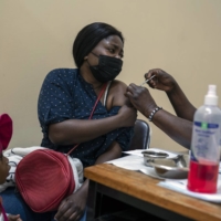 A woman receives a dose of COVID-19 vaccine in Johannesburg on Tuesday.  | JOAO SILVA / THE NEW YORK TIMES