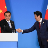 Former Prime Minister Shinzo Abe, seen here meeting with Chinese Premier Li Keqiang in December 2019, recently angered Beijing with remarks warning that a Chinese attack on Taiwan would be “economic suicide.” | POOL / VIA REUTERS