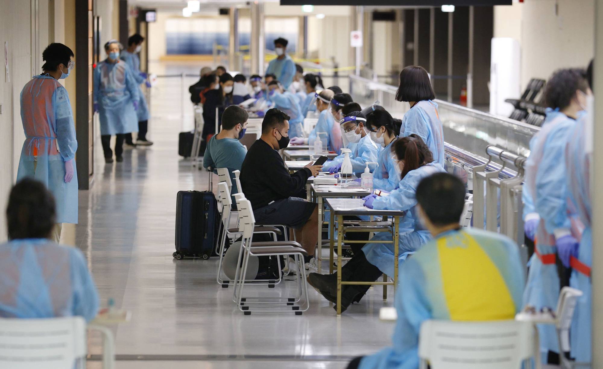 Arriving passengers undergo quarantine procedures at Narita Airport in Chiba Prefecture on Monday. | KYODO
