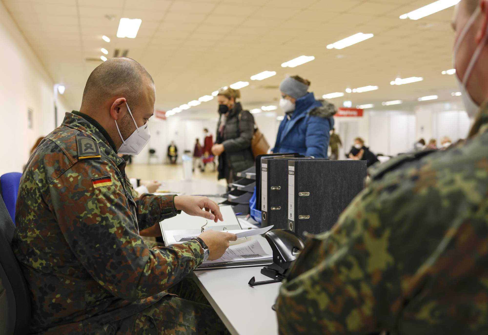 German Army soldiers assist the administration of COVID-19 vaccinations at a vaccine center in Munich, Germany, on Thursday. Germany is poised to clamp down on people who are not vaccinated against COVID-19 and drastically curtail social contacts, to ease pressure on increasingly stretched hospitals. | Bloomberg