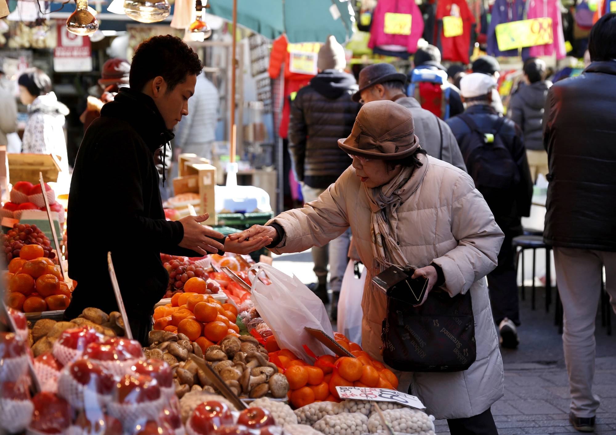 A woman buys fruit outside a vegetable store in Tokyo's Ameyoko shopping district. | REUTERS