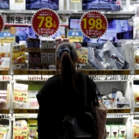A woman looks at items outside an outlet store at a shopping district in Tokyo. | REUTERS