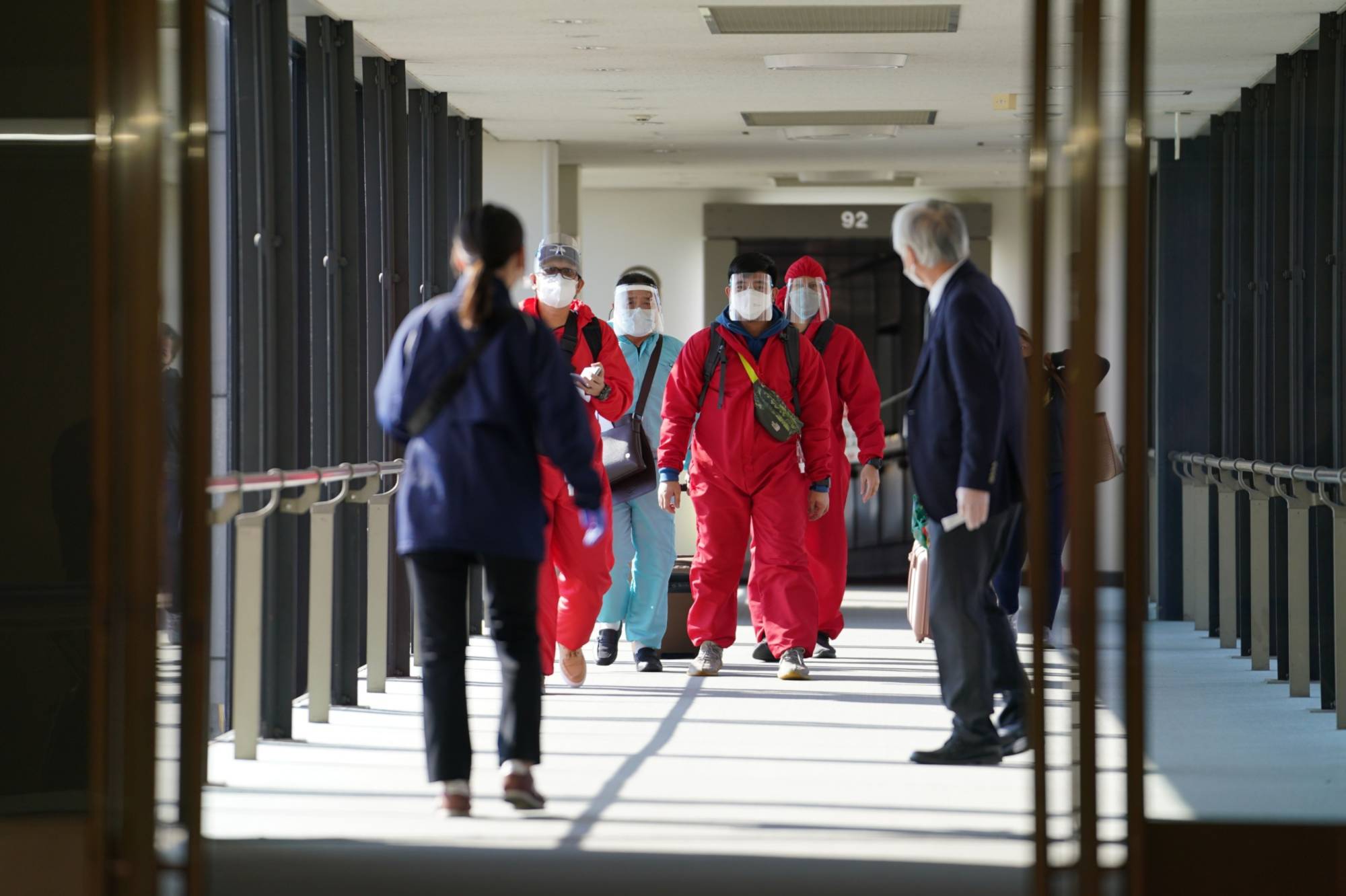 Travelers disembarking from a Philippine Airlines flight wearing personal protective equipment arrive at Narita Airport on Nov. 30. | BLOOMBERG