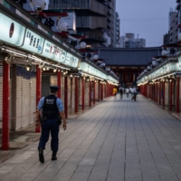 A police officer patrols along the Nakamise shopping street in Tokyo\'s Asakusa district in August. | GETTY IMAGES / VIA BLOOMBERG