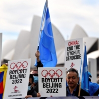 Protesters hold up placards and banners as they attend a demonstration in Sydney in June to call on the Australian government to boycott the 2022 Beijing Winter Olympics over China\'s human rights record. | AFP-JIJI