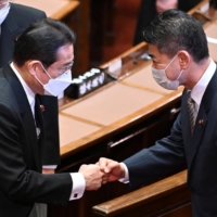 Prime Minister Fumio Kishida and Kenta Izumi, new leader of the main opposition Constitutional Democratic Party of Japan, greet each other after the opening ceremony of an extraordinary session of parliament in Tokyo on Monday. | AFP-JIJI